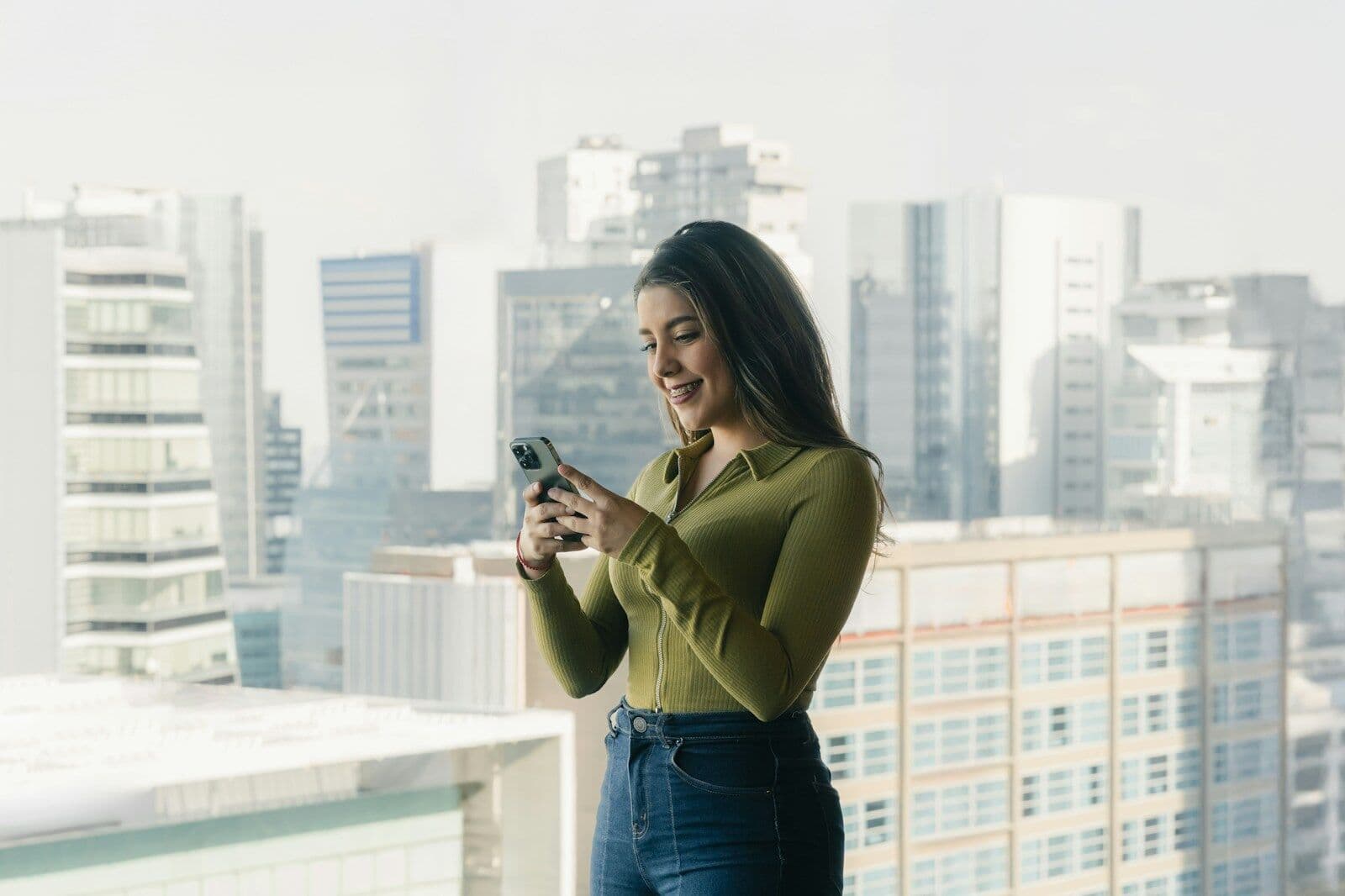 A woman checking her phone with new condo towers behind her