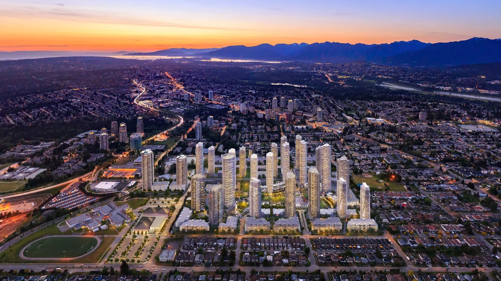 Southgate City – A dusk aerial view of a cluster of high-rise residential towers under construction or newly built, set within a large city with mountains and water visible in the distance.