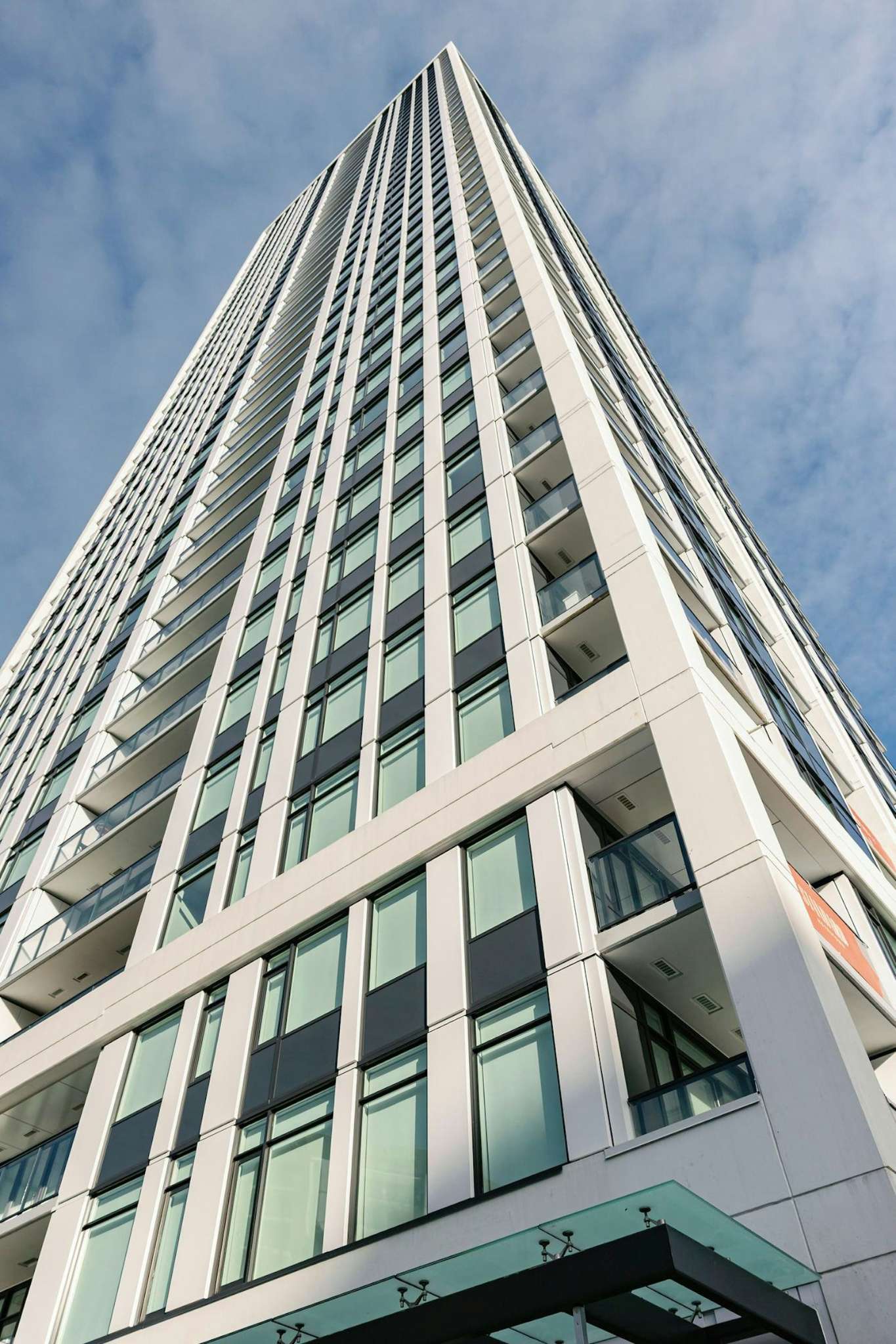 The Standard – Upward view of the tower's glass-and-white facade with balconies, shot from street level looking toward the sky.