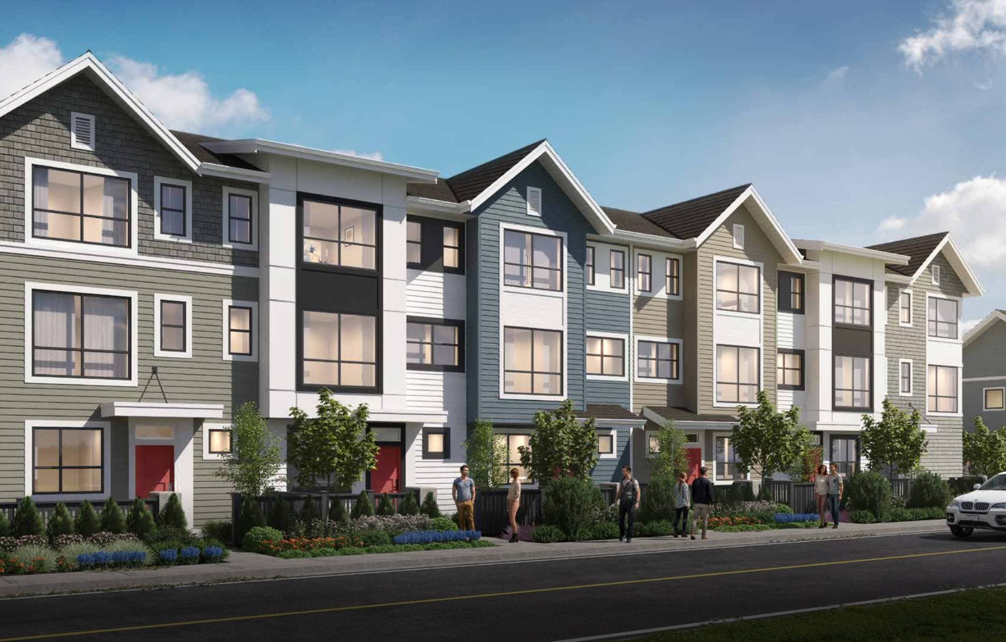 Silverbrook Townhomes – Row of three-story townhomes in varied gray, blue, and white siding along a street, with red front doors and pedestrians walking by.
