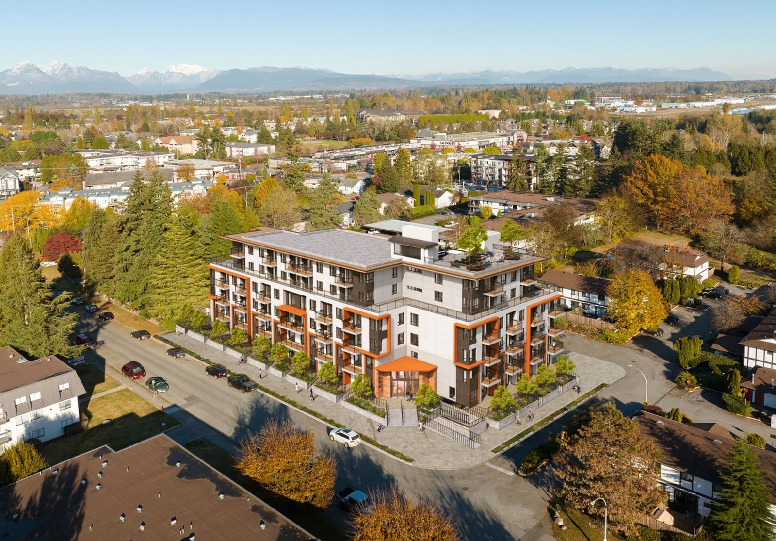 Véra – A drone view of the mid-rise development set among a residential neighbourhood, with mountains visible in the distance.