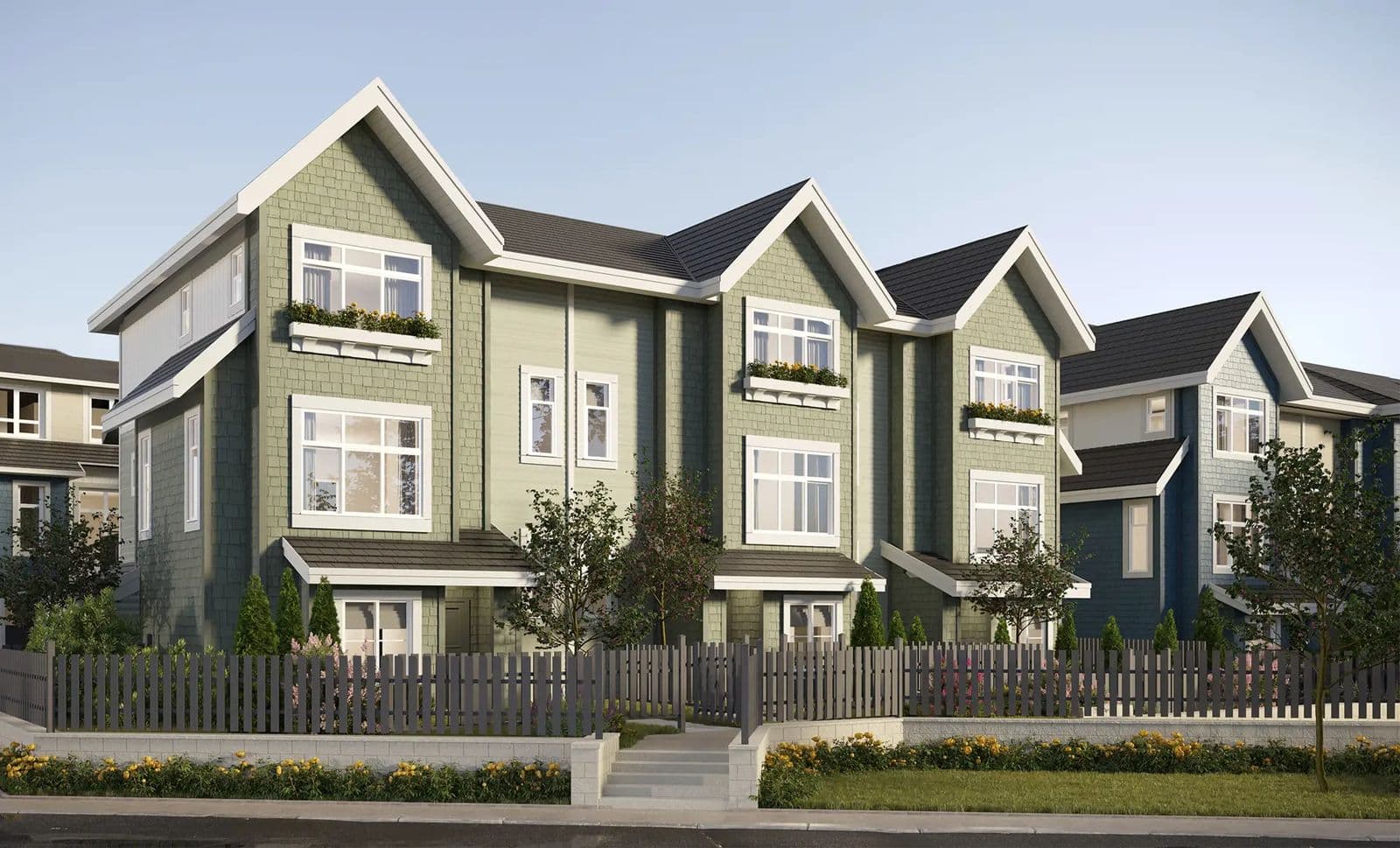 Provenance – Street-level view of green craftsman-style townhomes with white trim and flower boxes.