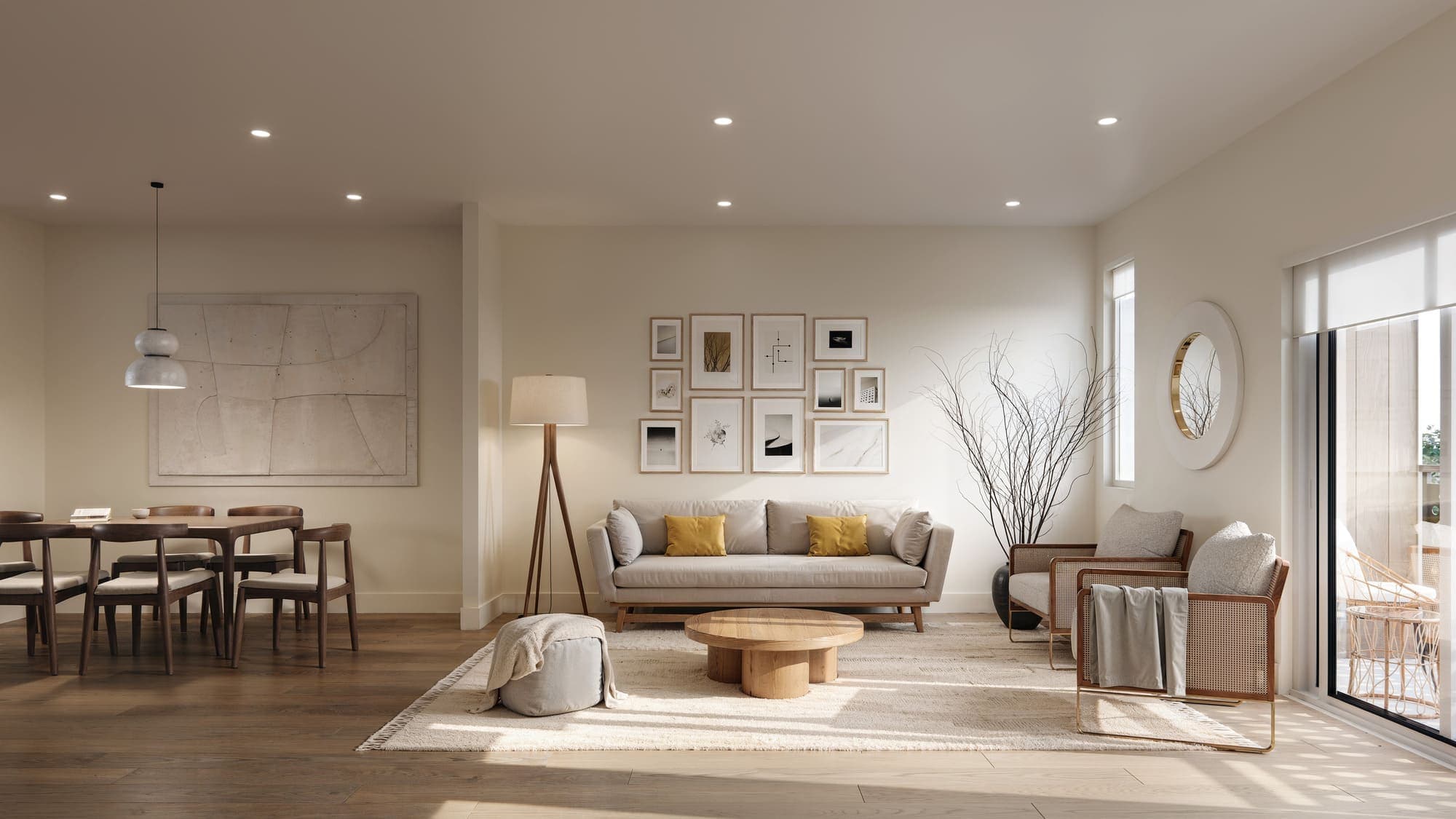 Oaklyn – A living and dining area with a beige sofa, wood coffee table, gallery wall of framed prints, dining table, and a round mirror by the balcony door.