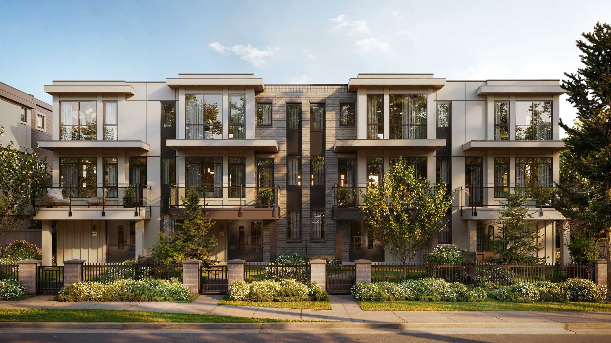 Quilchena West – Three-story modern townhome building with dark brick center accent, large windows, balconies, and a landscaped front yard with iron fencing.