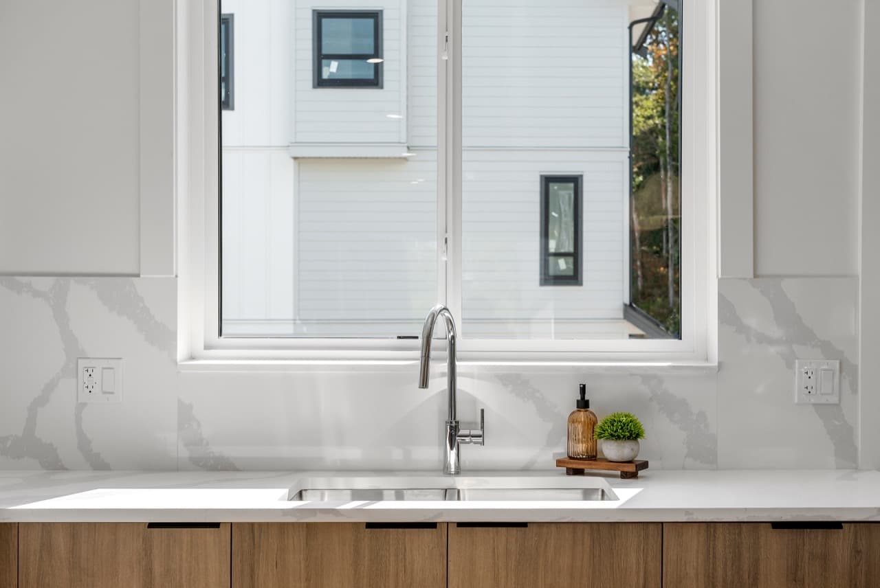 Signature – Kitchen sink area beneath a window looking out at neighboring townhomes.