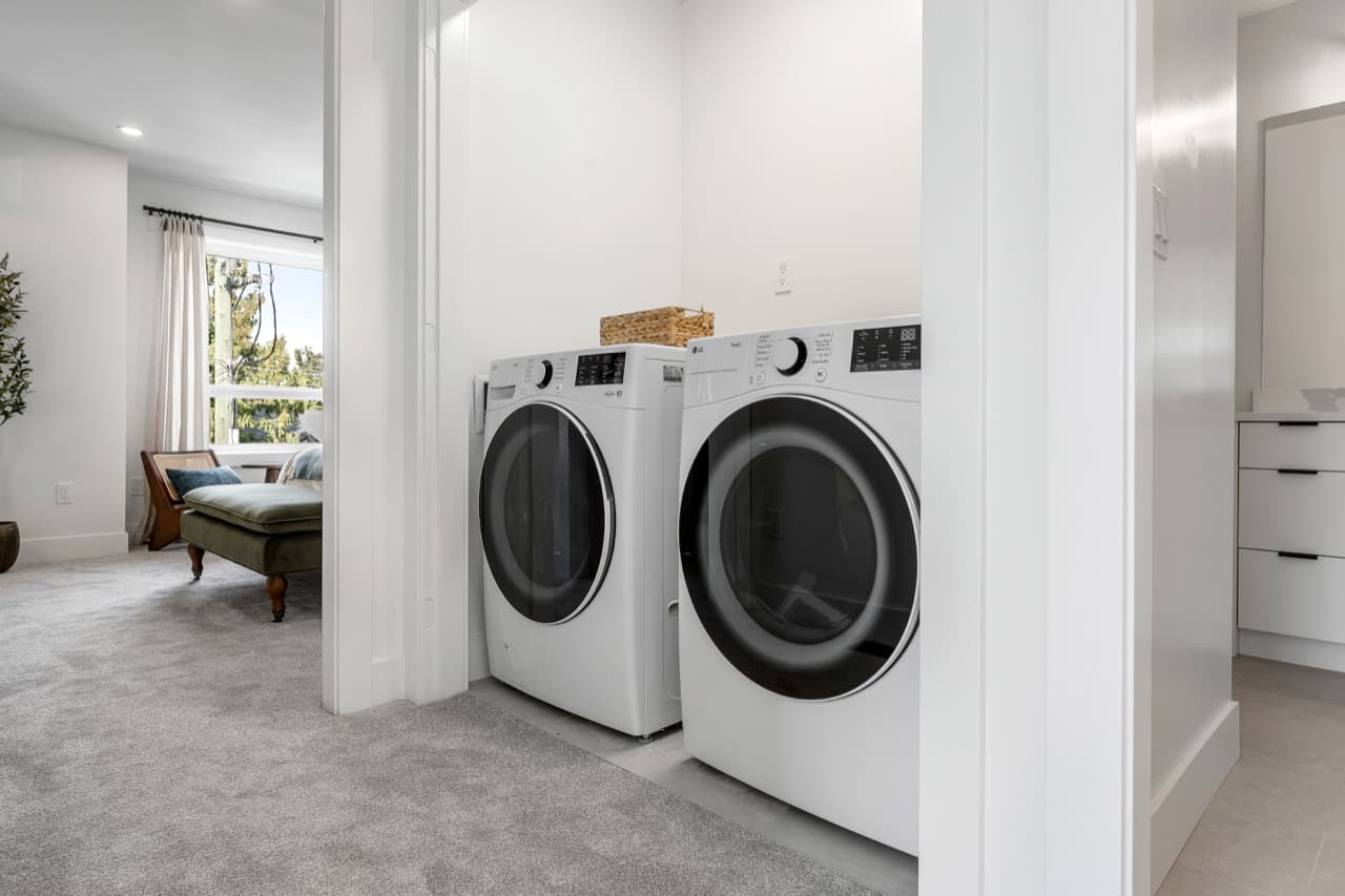 Signature – Laundry closet with a front-load washer and dryer, with a view into a bedroom beyond.