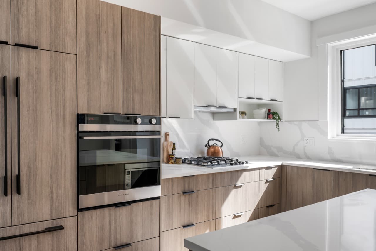 Signature – Kitchen with a built-in wall oven, gas cooktop, and wood cabinetry.