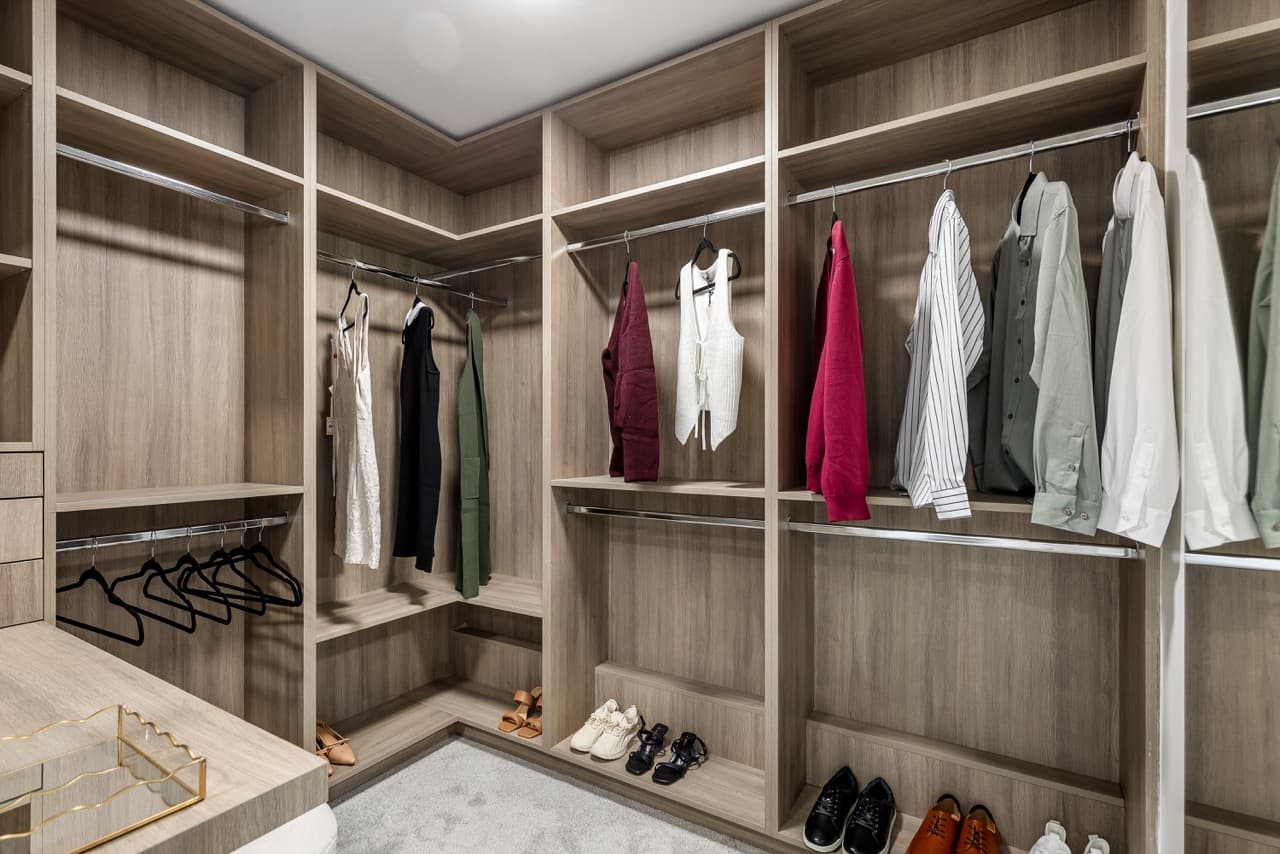Signature – Walk-in closet with built-in wood shelving, hanging clothes, and shoe storage.