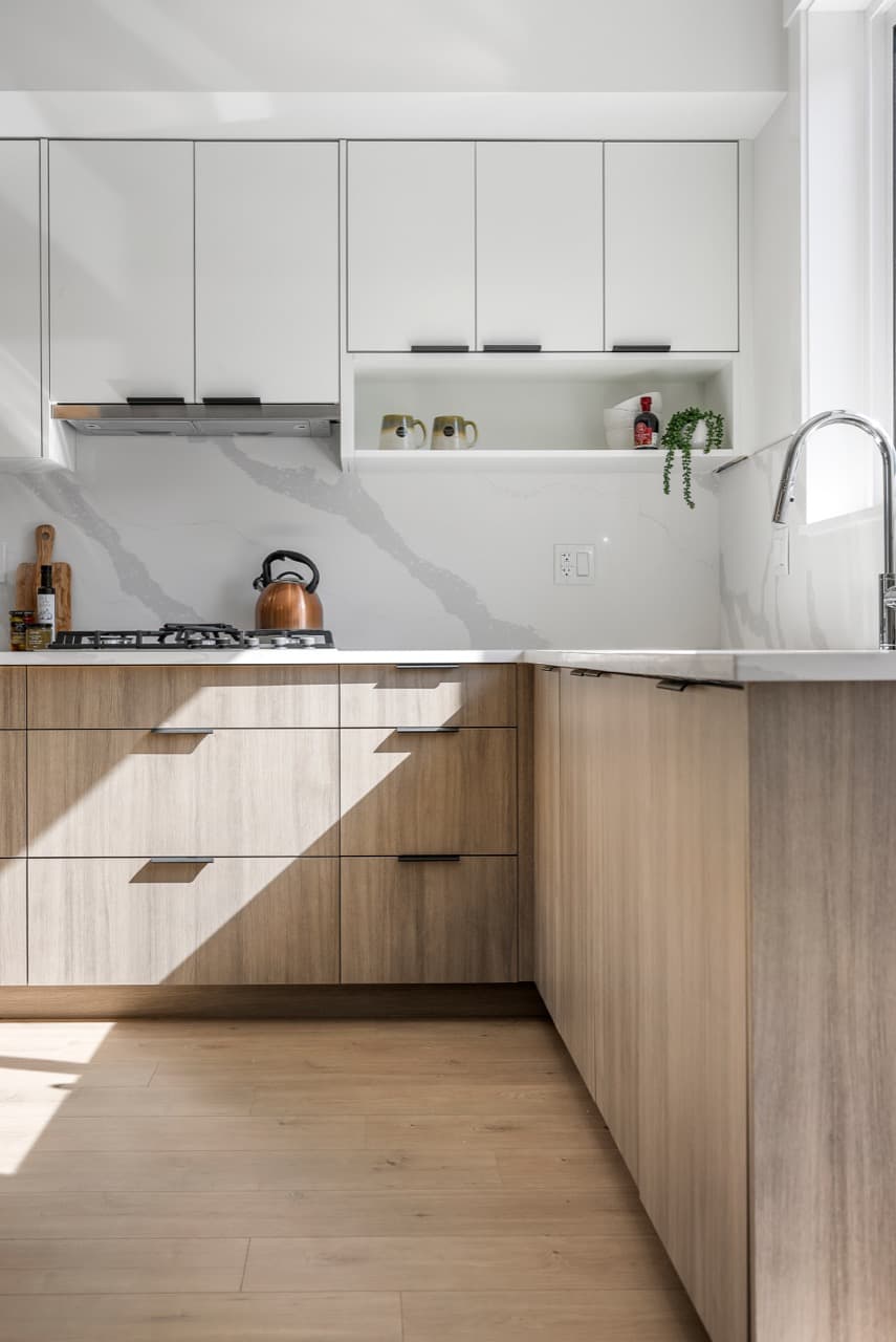 Signature – Kitchen counter with a gas cooktop, copper kettle, and wood-finish cabinetry below a marble backsplash.
