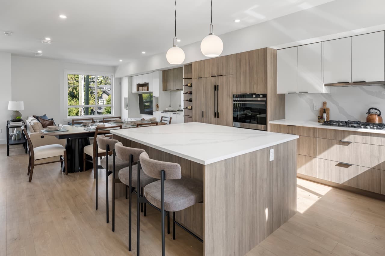Signature – Kitchen island with bar seating and pendant lighting, overlooking the open living and dining area.