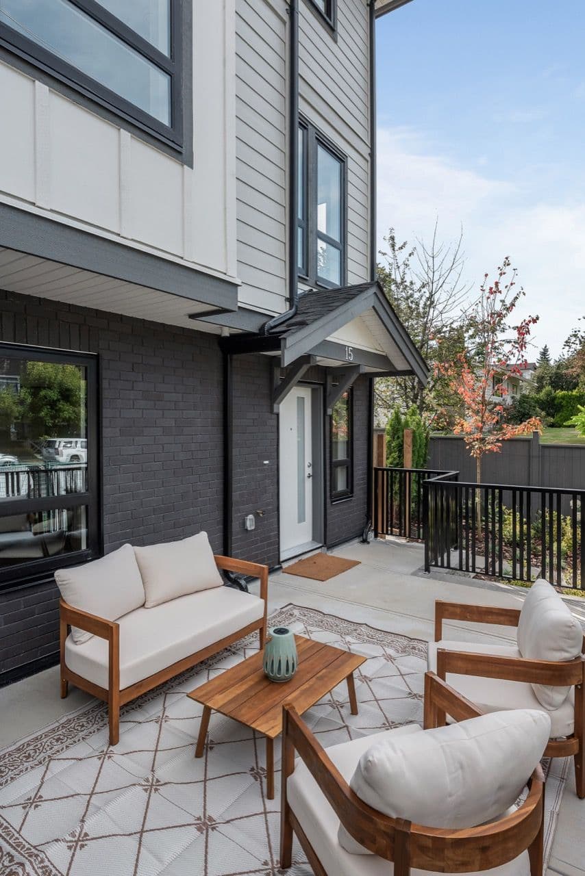 Signature – Front patio and entrance of unit 15, showing dark brick facade and outdoor lounge furniture on the deck.