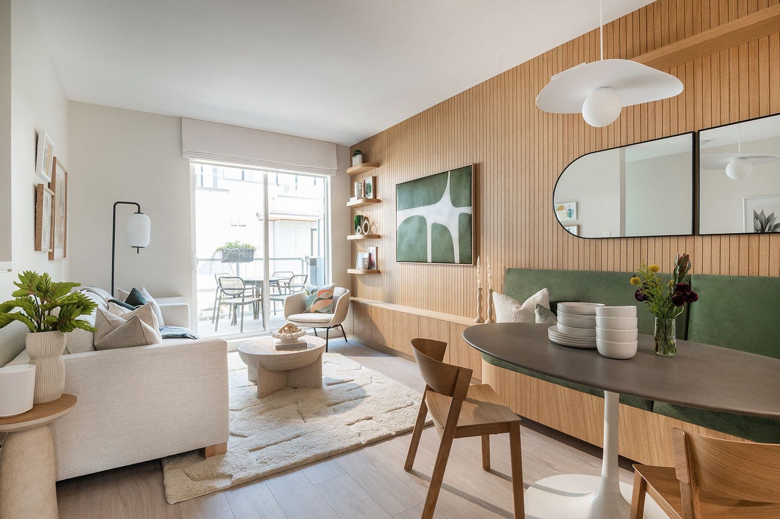 Sundays on Grant – An open-concept living and dining room with a slatted wood accent wall, built-in banquette seating, and sliding doors to a balcony.