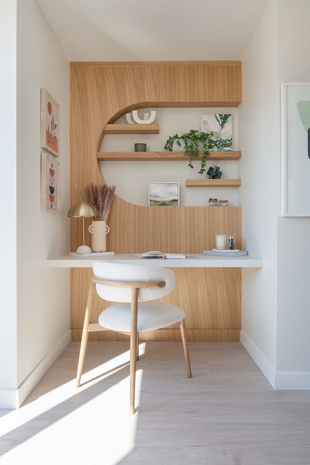Sundays on Grant – Built-in office desk alcove with curved wooden wall panelling, floating shelves, desk chair, and decorative objects.