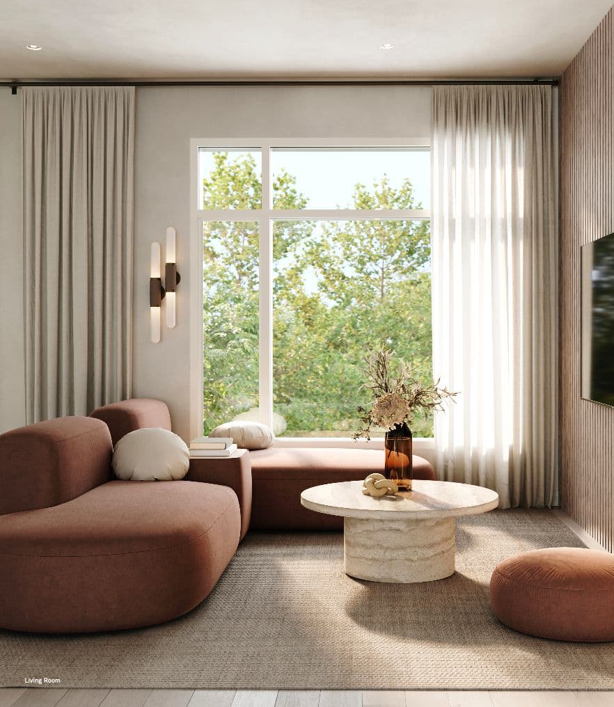 Rowen W47th – Living room with a curved rust-colored sectional sofa, round travertine coffee table, and a large window looking out to trees.