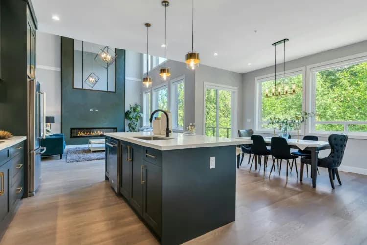 Marble Hill – Kitchen with dark blue cabinetry, waterfall island, and view through to a dining area and fireplace lounge, same great room as other photos from a different angle.