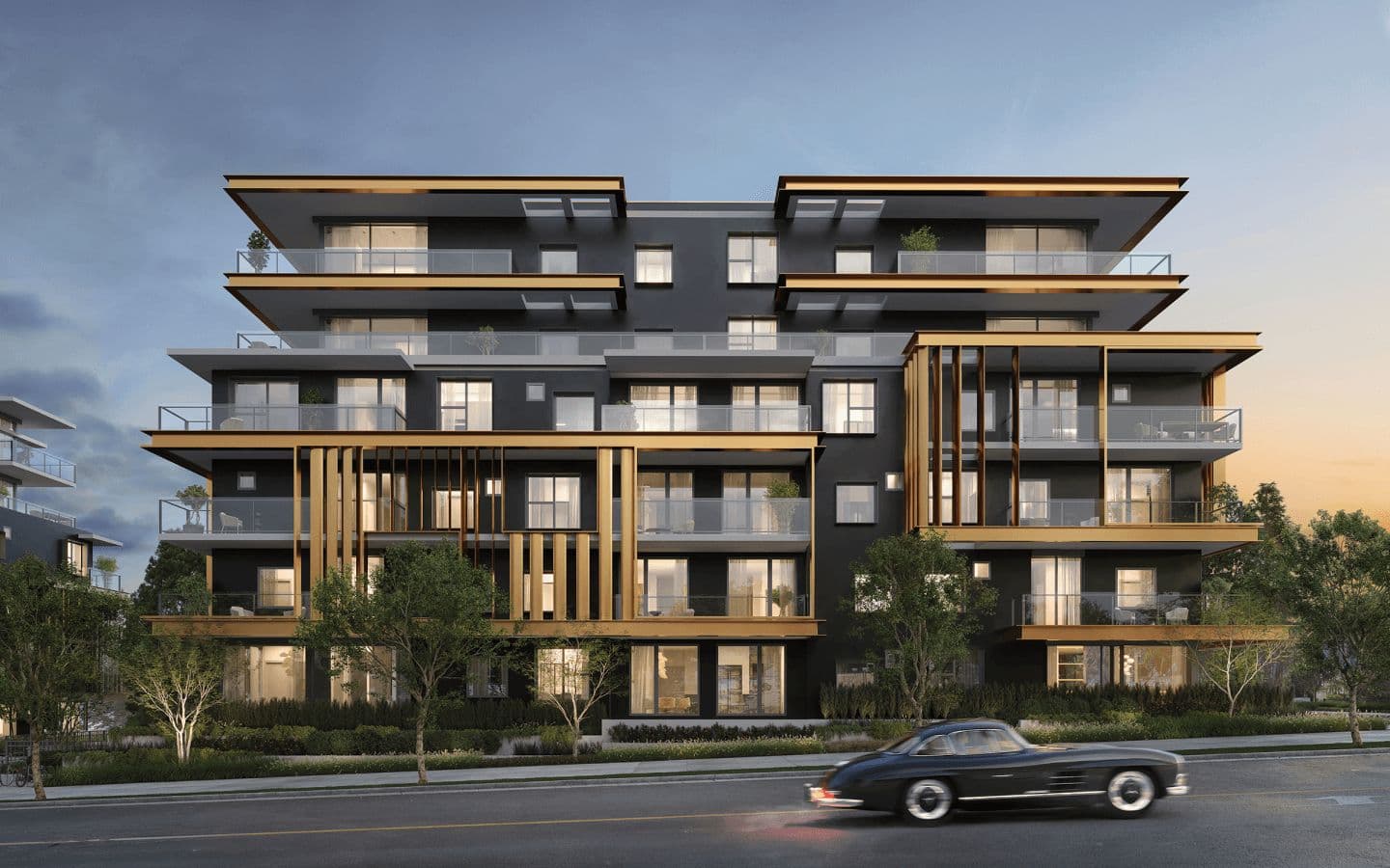 Fränk – A modern, mid-rise residential building features a dark facade accented with metallic gold horizontal overhangs, vertical slats, and glass balcony railings. A classic sports car drives along the paved street in the foreground, past young trees and street-level landscaping under a dusk sky.