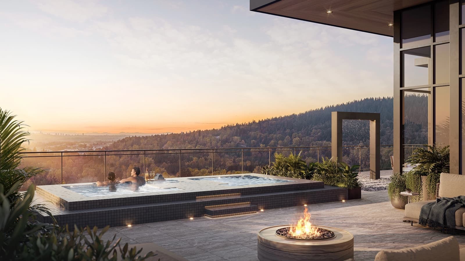 Komo – Rooftop infinity-edge hot tub with two people relaxing, a fire pit, lounge seating, and sweeping sunset views over forested hills and a distant city.