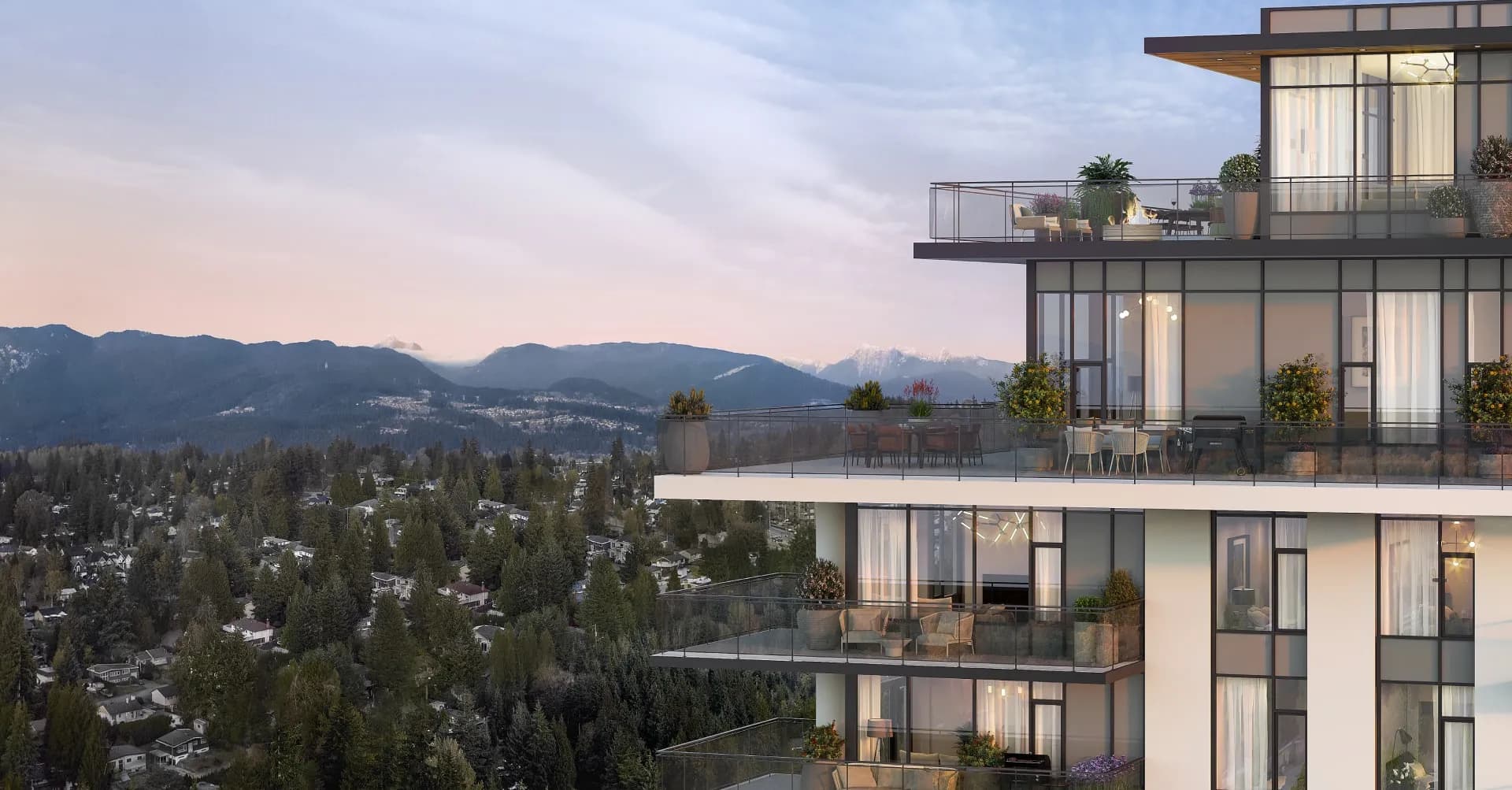 Komo – Close-up exterior view of the tower's upper floors and private balconies at dusk, with mountain peaks and a treed valley in the background.