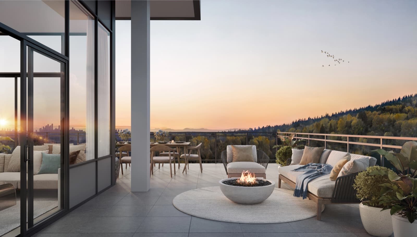Komo – Sunset view from a private balcony with lounge seating and a fire bowl, overlooking a forested hillside with a distant city skyline.