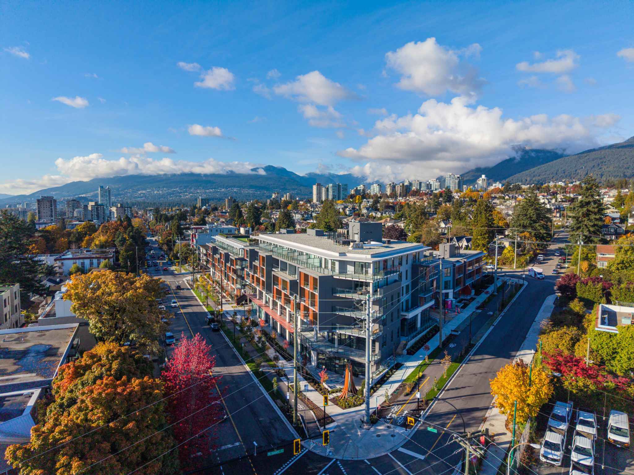 Innova – Autumn aerial view of the multi-story building along a tree-lined street with mountains and city skyline in the distance.
