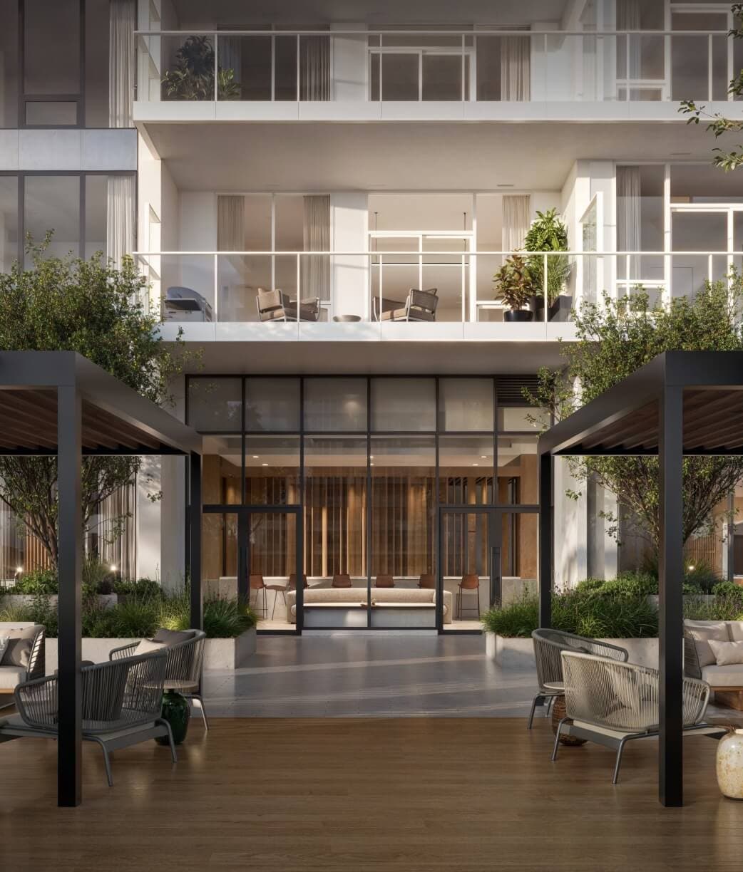 The Amazing Brentwood – Outdoor courtyard lounge with pergolas, seating areas, and greenery leading into an indoor lobby lounge with a sofa and bar stools.