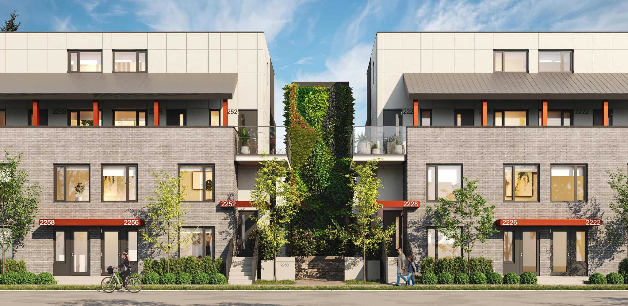 Templeton – Street-level view of a row of light-brick townhomes with orange awning signage over each entry and greenery between units.