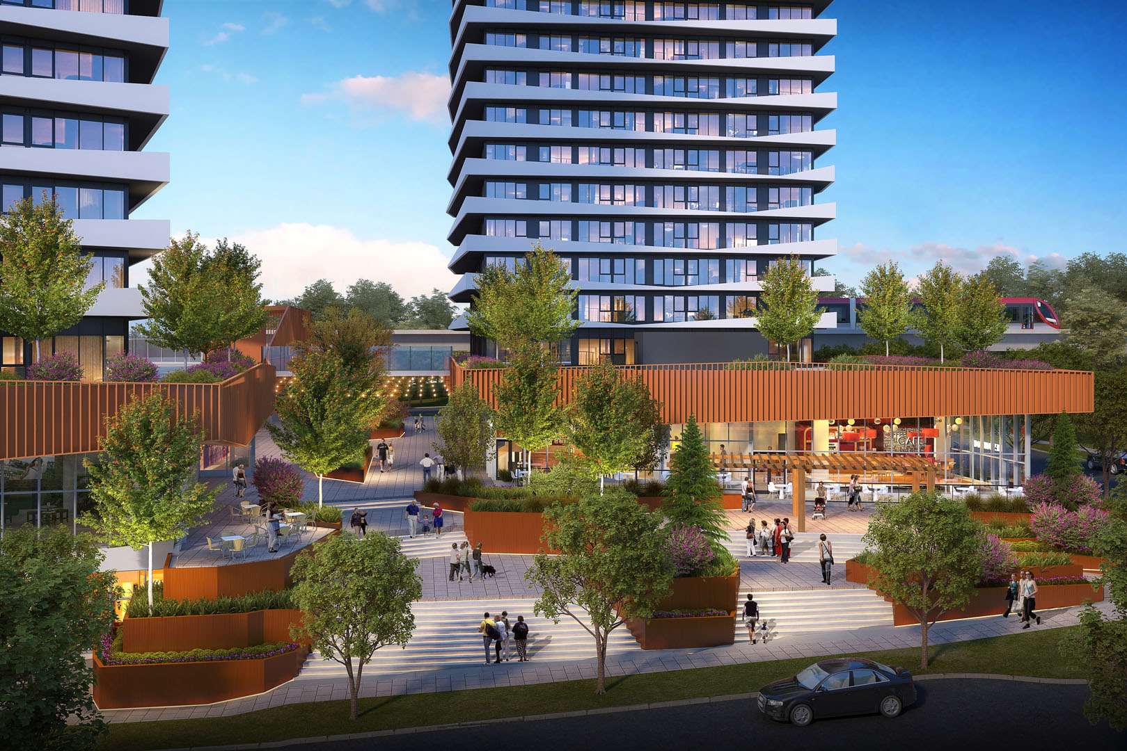 Orion – An elevated view of a bustling pedestrian plaza and retail base featuring warm wood-slat overhangs, stepped terraces, and leafy landscaping at the foot of modern high-rise residential towers. Pedestrians stroll past ground-floor cafes and outdoor seating, with a commuter train visible along an elevated track in the background under a clear daytime sky.