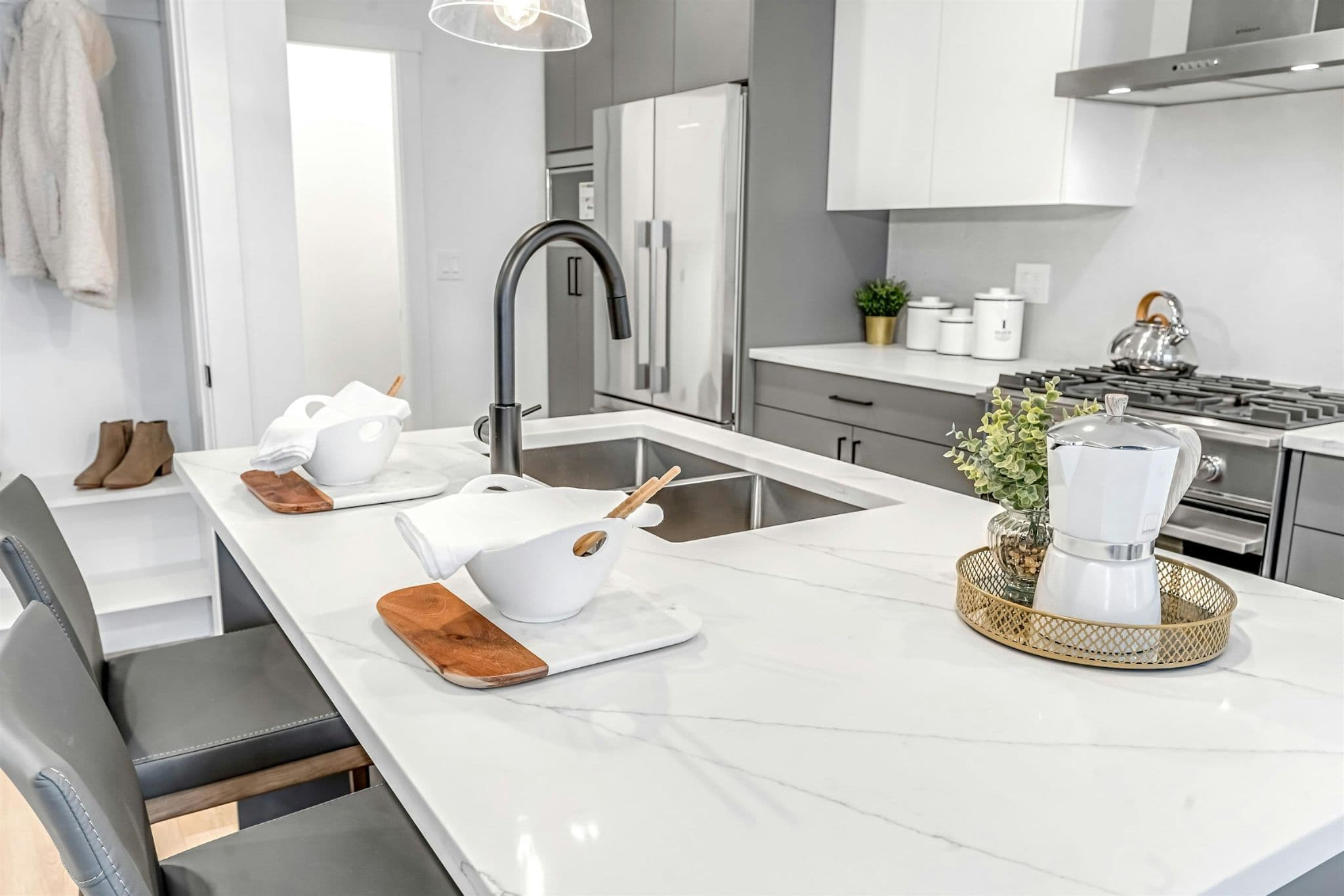Park Avenue Townhomes – A modern kitchen island featuring white quartz countertops, an undermount double sink with a black faucet, and bar seating.