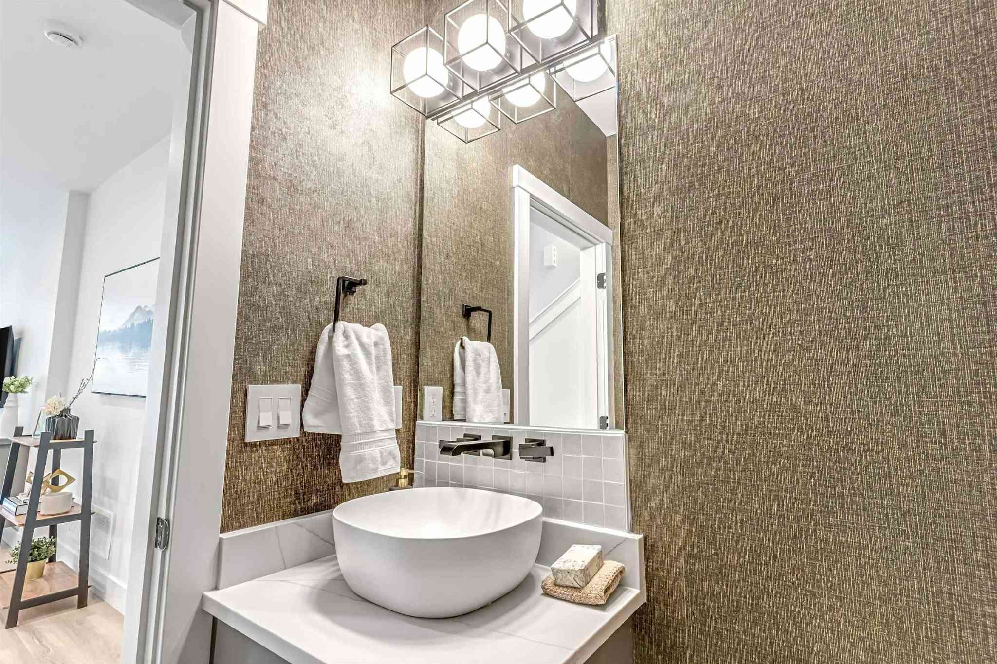 Park Avenue Townhomes – A powder room featuring textured wallpaper, a vessel sink with wall-mounted fixture, and a vertical mirror with cubic lighting.