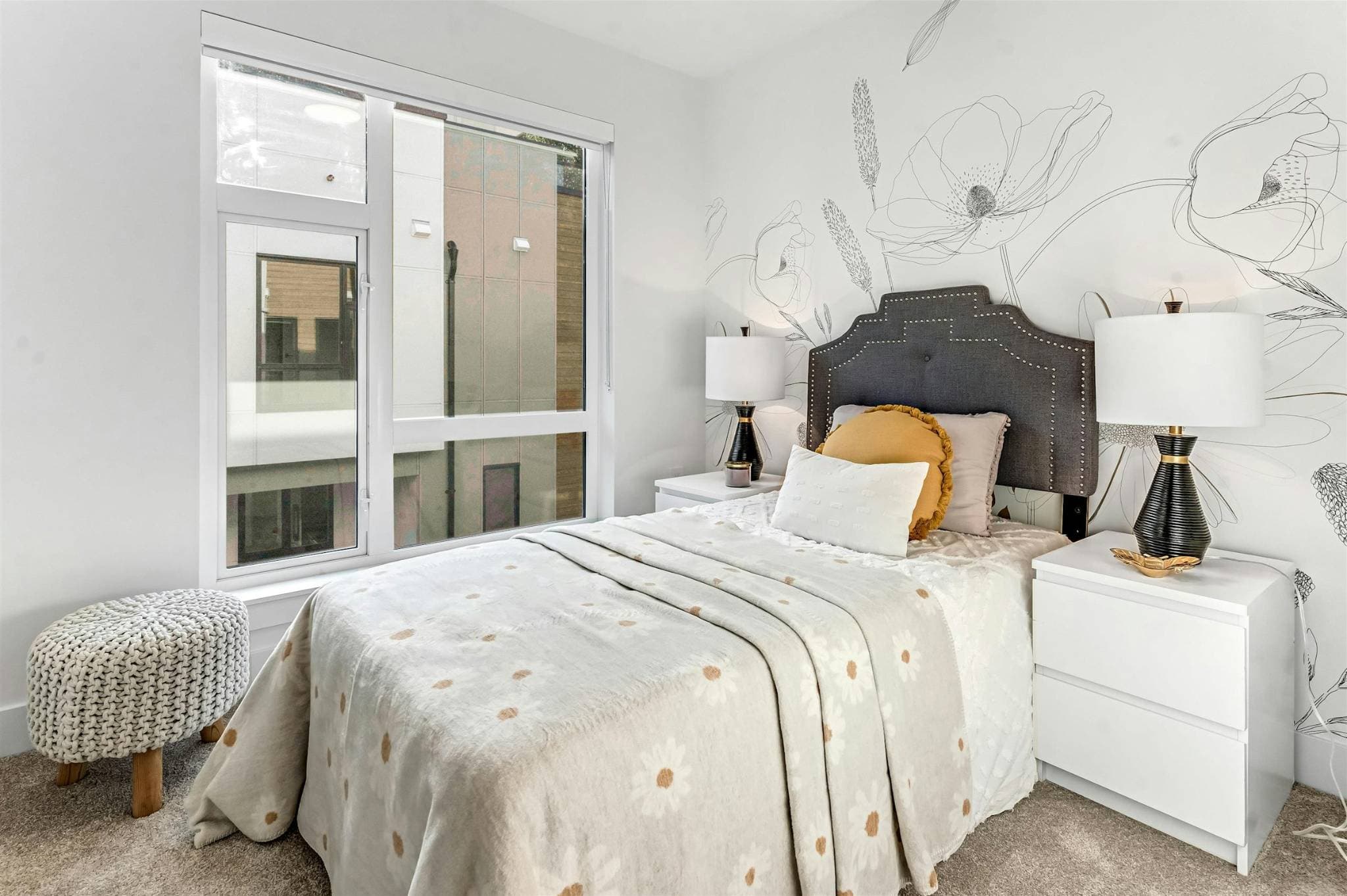 Park Avenue Townhomes – A styled bedroom featuring a single bed with an upholstered dark headboard, floral accent wall mural, and side nightstands with table lamps.