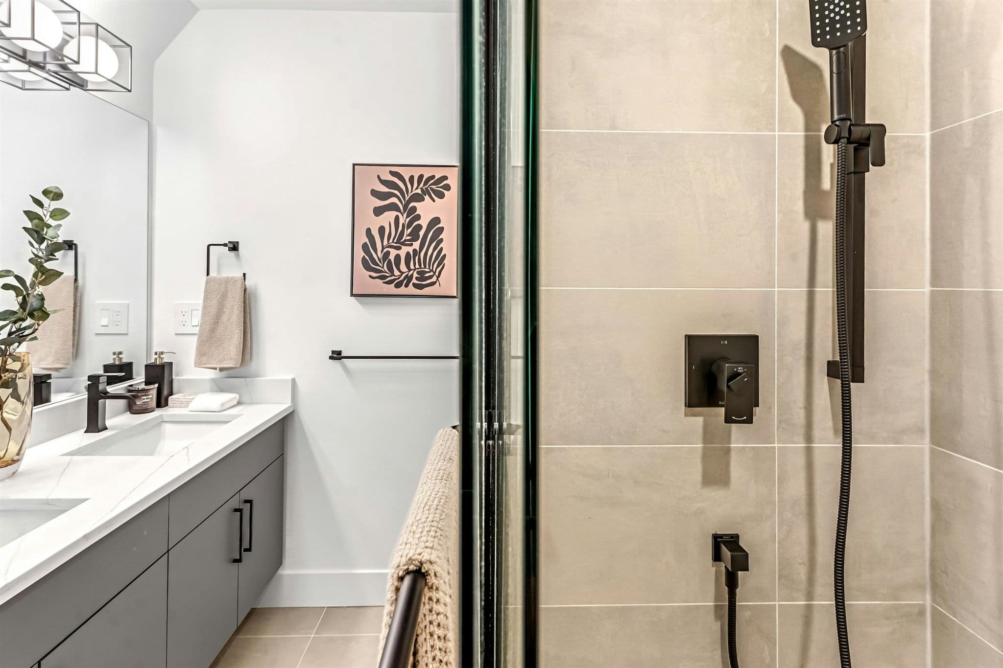 Park Avenue Townhomes – A close-up view inside a tiled shower enclosure with black hardware, looking toward the bathroom double vanity.