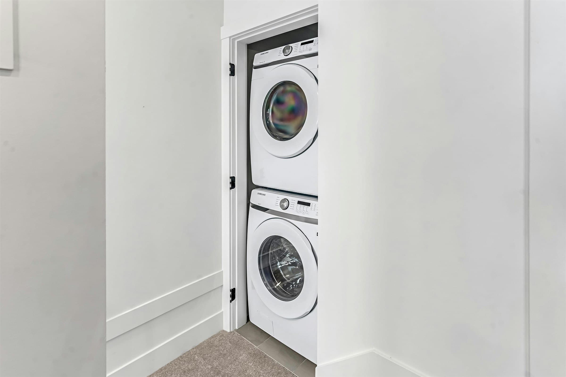 Park Avenue Townhomes – A laundry closet with stacked front-loading white Samsung washer and dryer appliances.