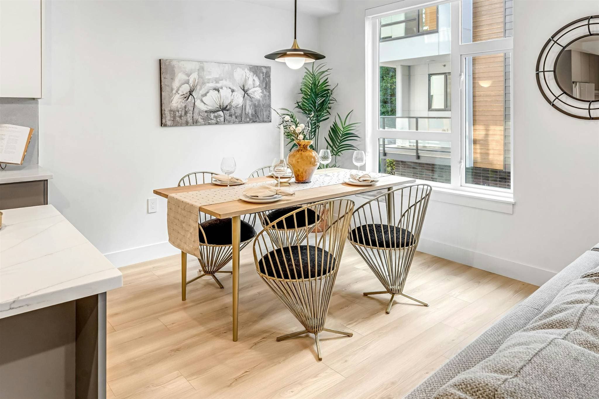 Park Avenue Townhomes – A dining space set with a wooden dining table, wire-back chairs, floral artwork, and large window.