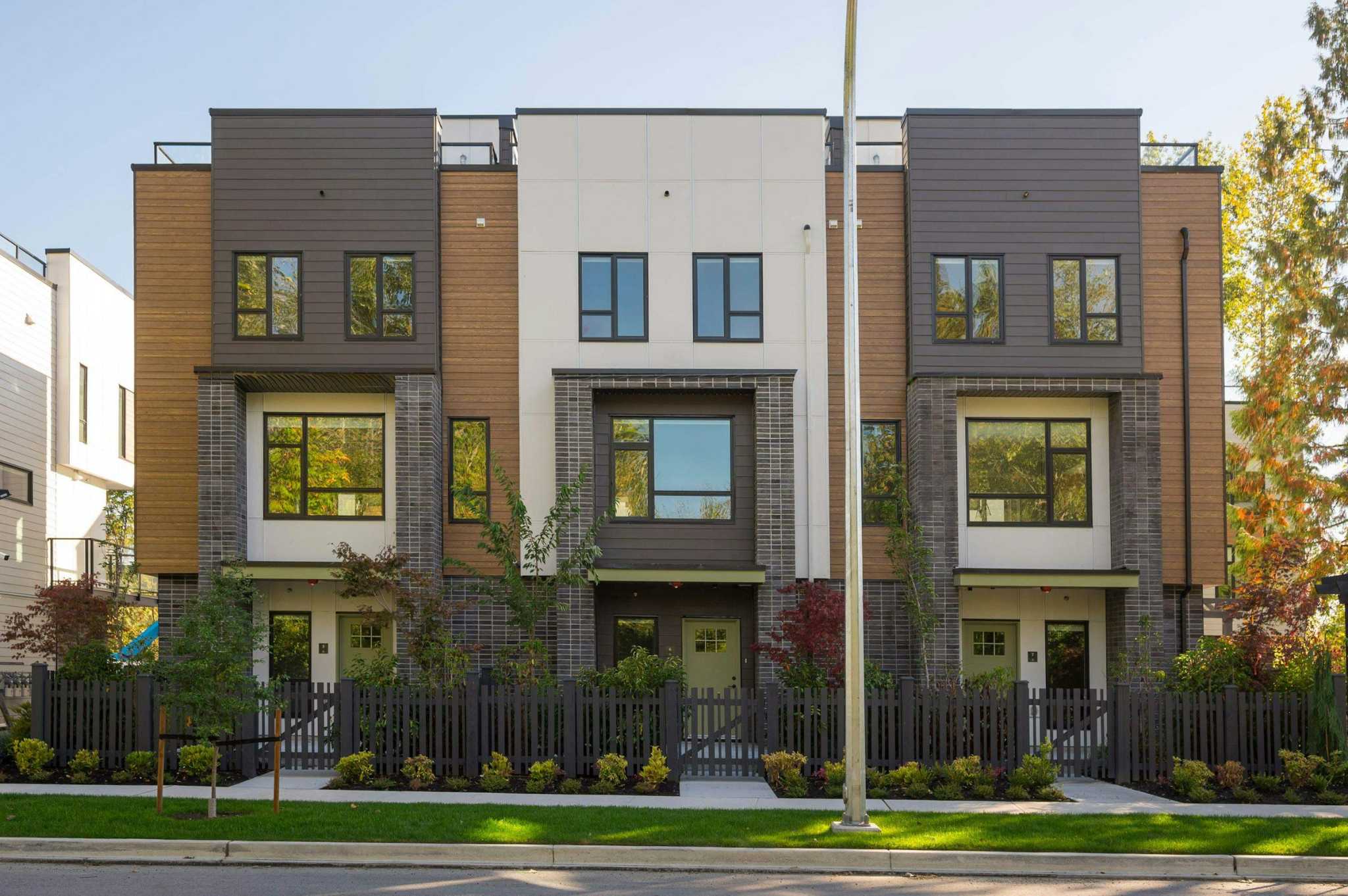Park Avenue Townhomes – Front exterior elevation of three-story townhomes with mixed brick, wood-grain, and panel exterior finishing and gated front entries.