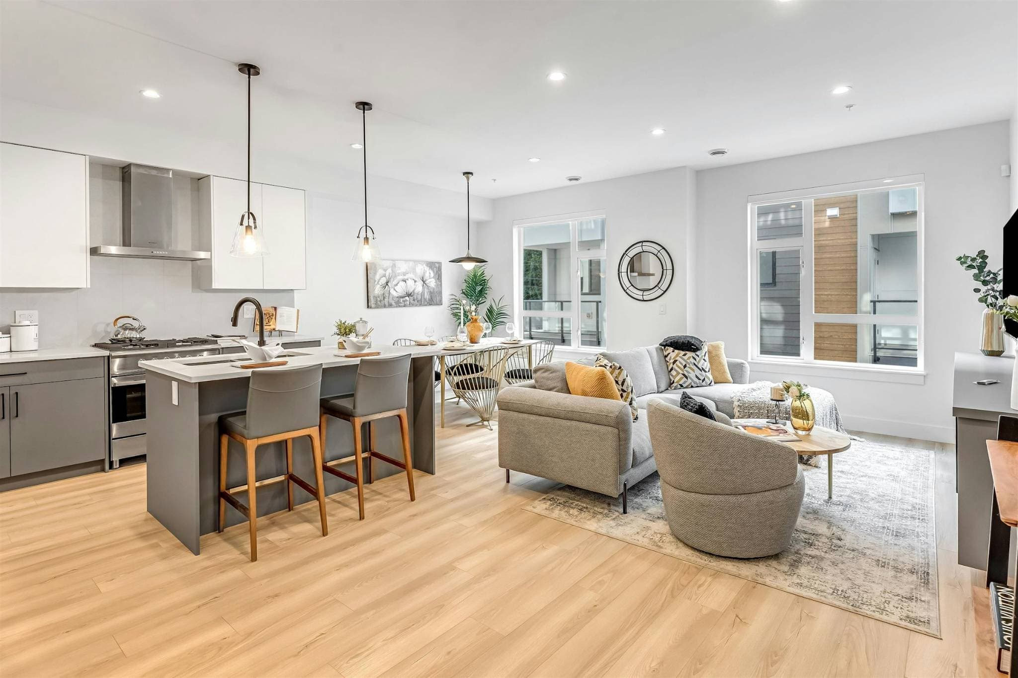 Park Avenue Townhomes – Wide shot of an open-concept main floor showing the kitchen island with bar stools, dining area, and full living room lounge.