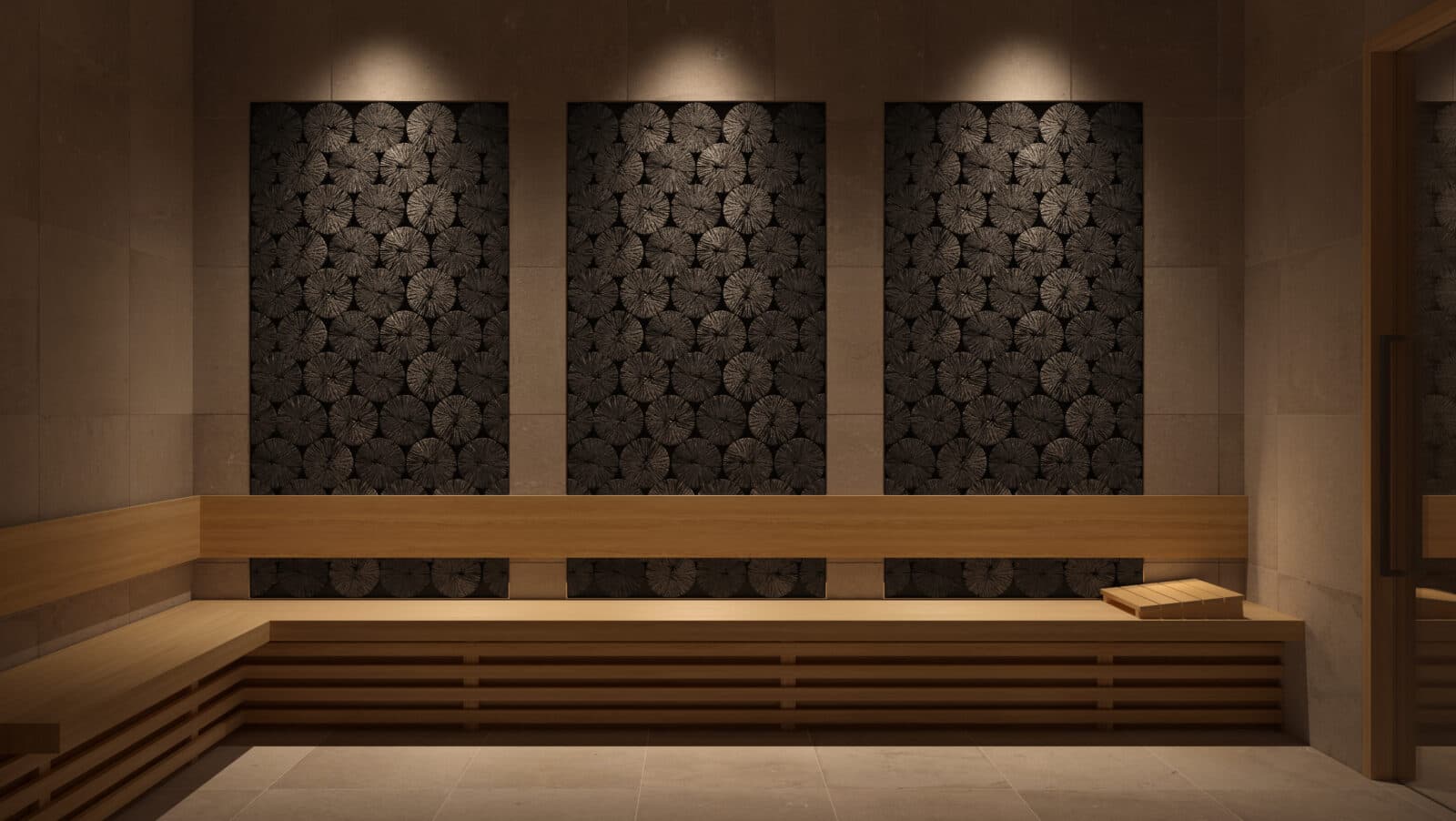 Jinju – A modern, dimly lit sauna room featuring a long L-shaped wooden bench and a small headrest against a stone-tiled wall. Three decorative recessed panels filled with circular textured wood log ends are illuminated from above by warm spotlighting, creating a tranquil spa ambiance.