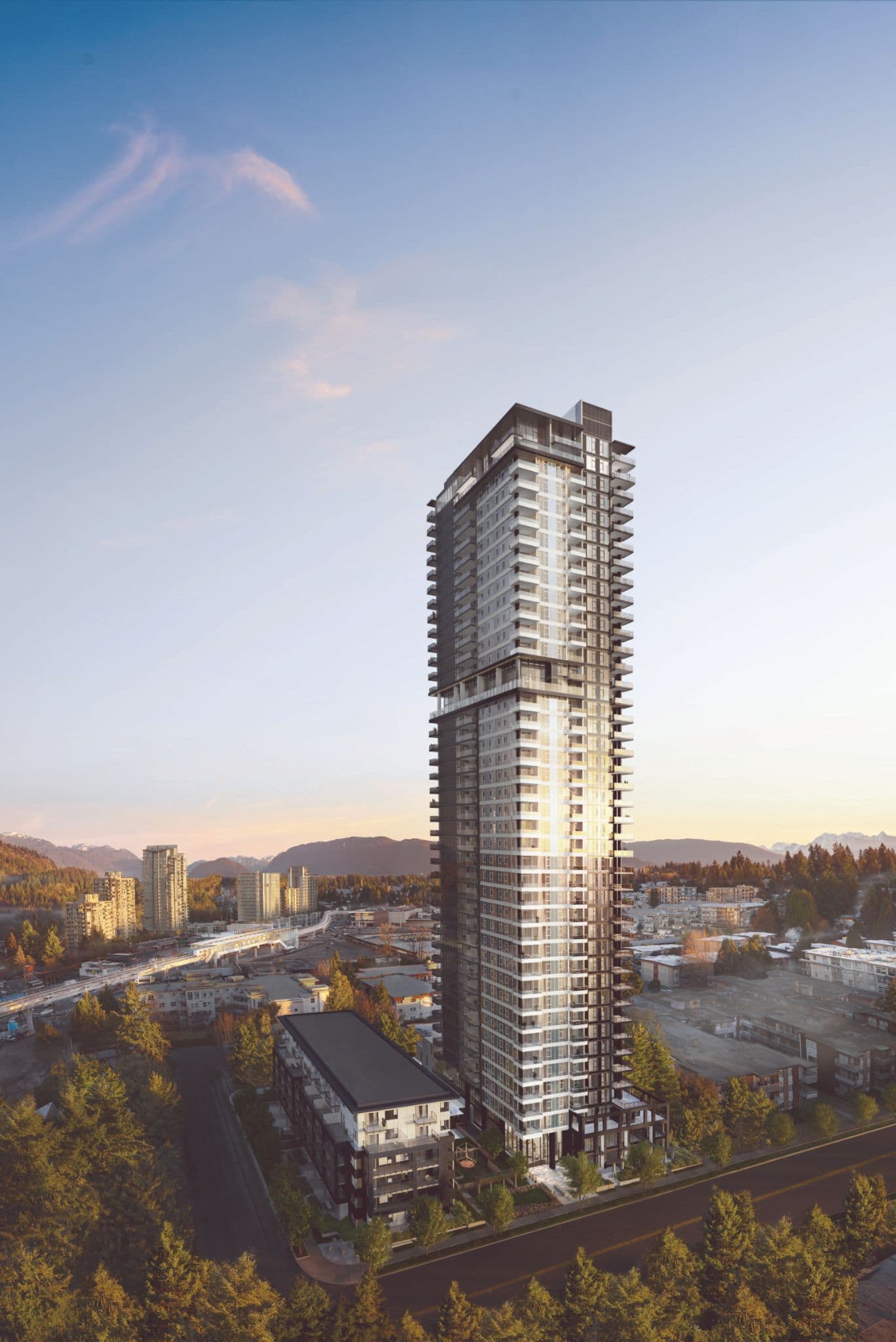 Jinju – An elevated view of a sleek, modern high-rise residential tower with wrap-around balconies and an adjacent mid-rise building. The surrounding neighbourhood features tree-lined streets, a transit line, and distant mountain silhouettes under a warm, late-afternoon sky.