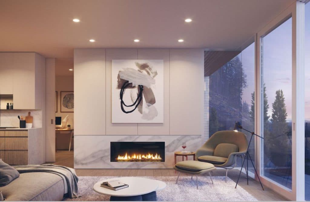 Alpine – Living room with a linear gas fireplace, abstract artwork above, and a lounge chair beside floor-to-ceiling windows looking onto trees.