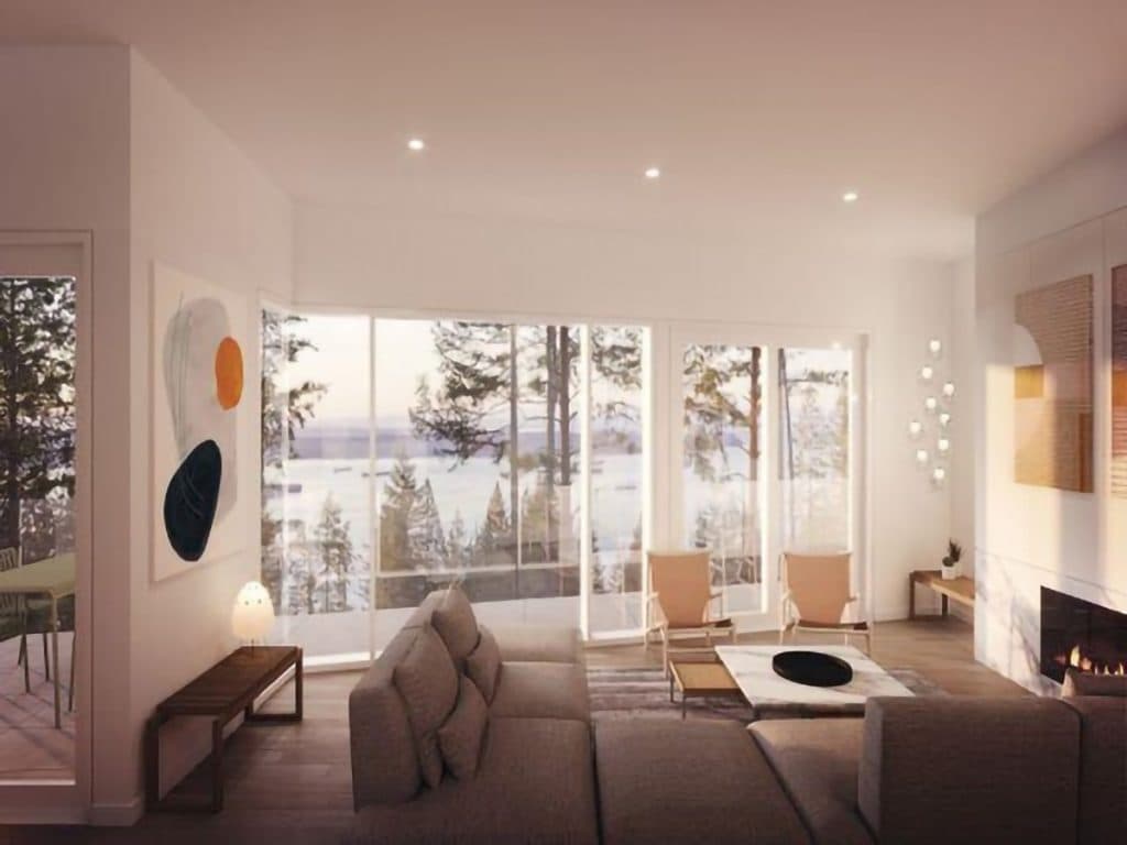 Alpine – Living room with a sectional sofa and wall art, floor-to-ceiling windows showing trees and a water view beyond.