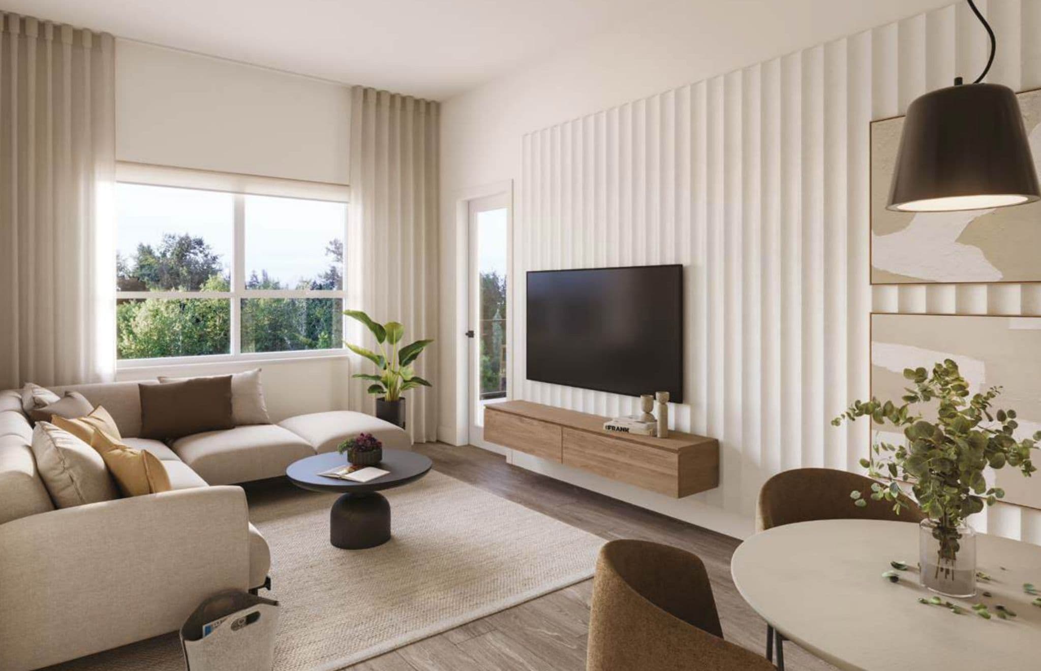 Eden – Living room with a beige sectional sofa, round coffee table, wall-mounted TV on a fluted accent wall, and a small dining table nearby.