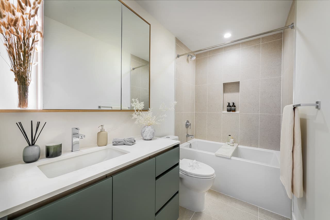 Century City Holland Park - Park Tower 1 – Bathroom with a green vanity, tiled tub-shower combo with a built-in niche, and a wood-framed medicine cabinet.