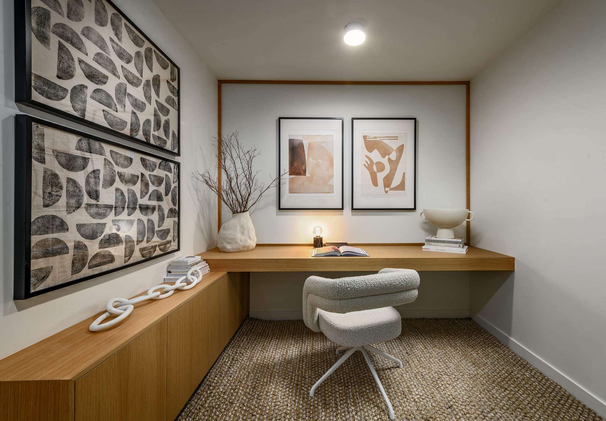Century City Holland Park - Park Tower 1 – Home office nook with a built-in wood desk, boucle swivel chair, framed artwork, and a woven jute rug.