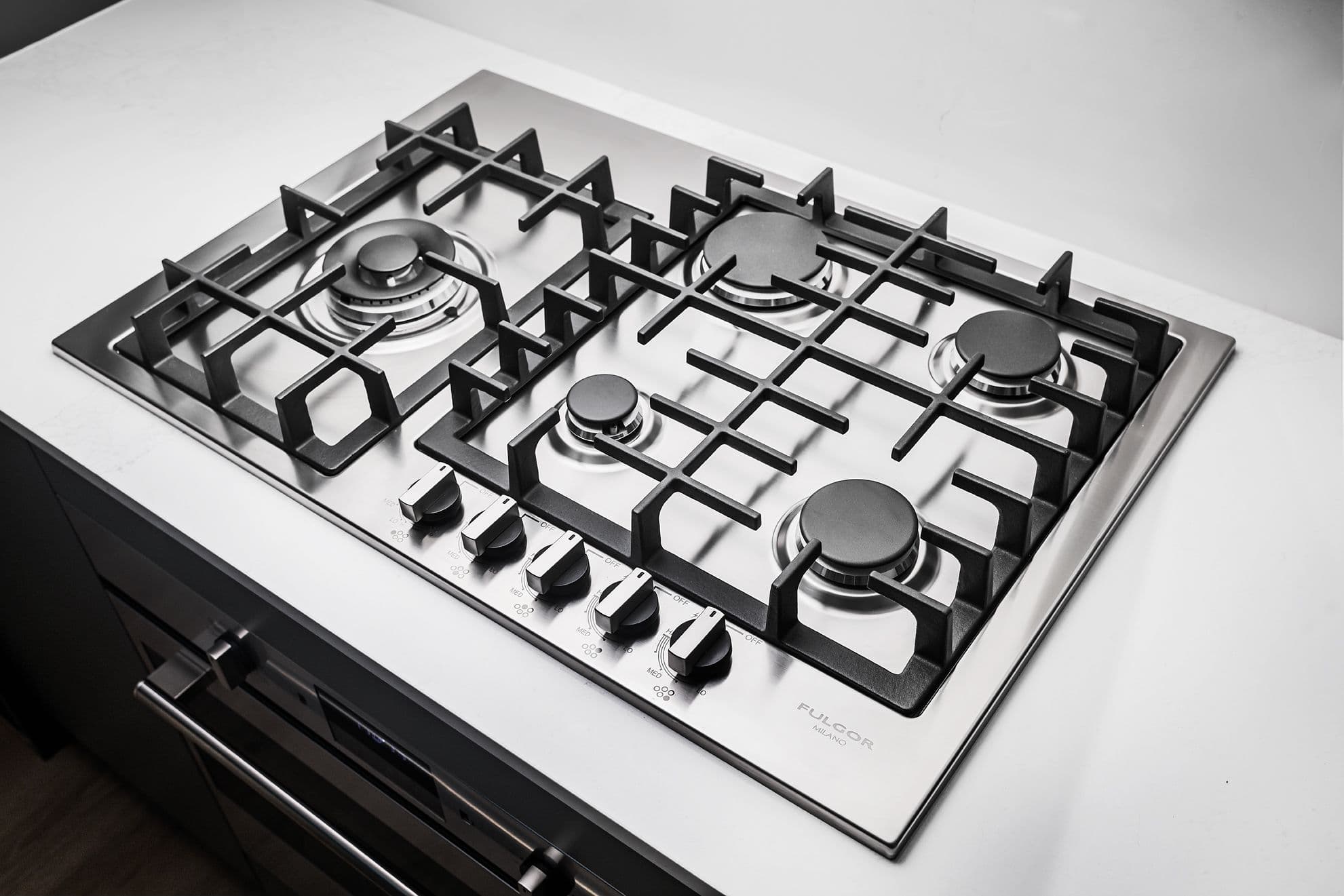 Century City Holland Park - Park Tower 1 – Close-up of a stainless steel five-burner gas cooktop with cast iron grates set into a white countertop.