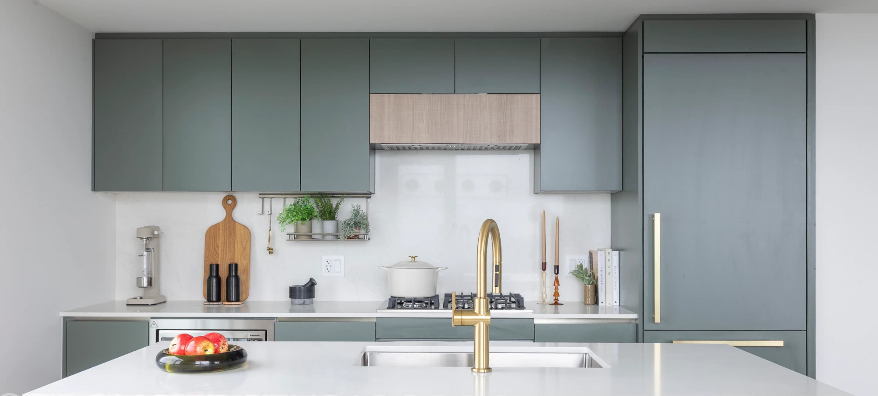 Century City Holland Park - Park Tower 1 – Kitchen with sage green cabinetry, a gold gooseneck faucet, gas cooktop, and built-in paneled refrigerator.