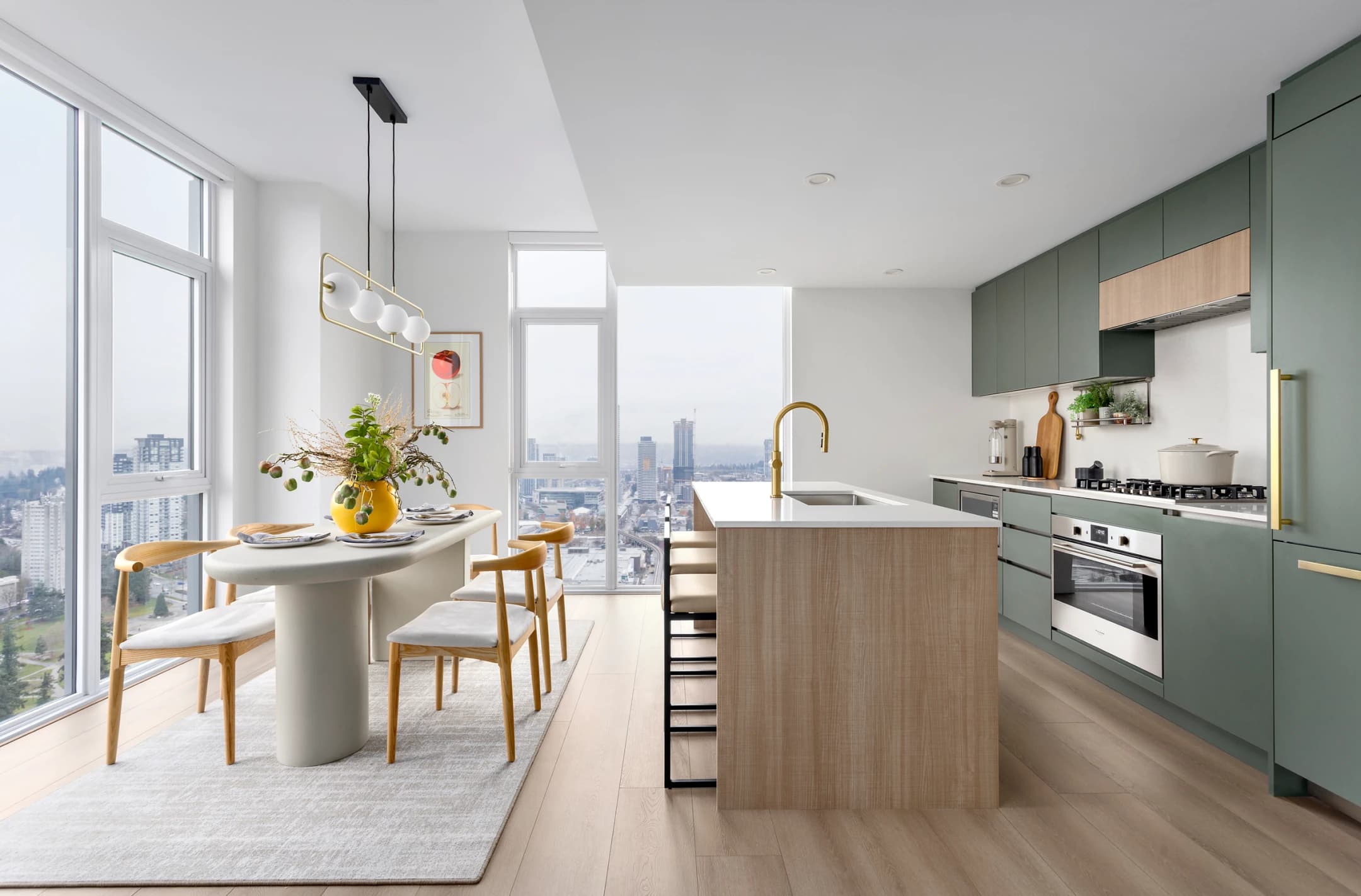 Century City Holland Park - Park Tower 1 – High-floor kitchen and dining area with green cabinetry, a wood island, gold faucet, and floor-to-ceiling windows overlooking a hazy city skyline.