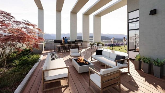 Ovation – Rooftop lounge deck with a fire pit, white outdoor sofas and chairs, surrounded by tall columns with mountain views in the background.