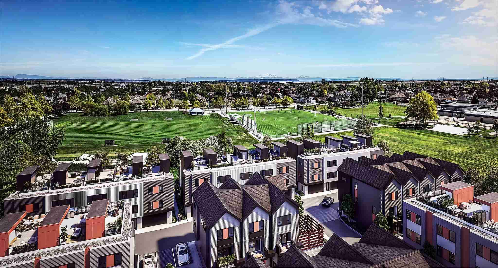 Skye at Holly Park – Aerial drone rendering over the townhome rooftops and rooftop patios, looking out over a park with mountains on the horizon.