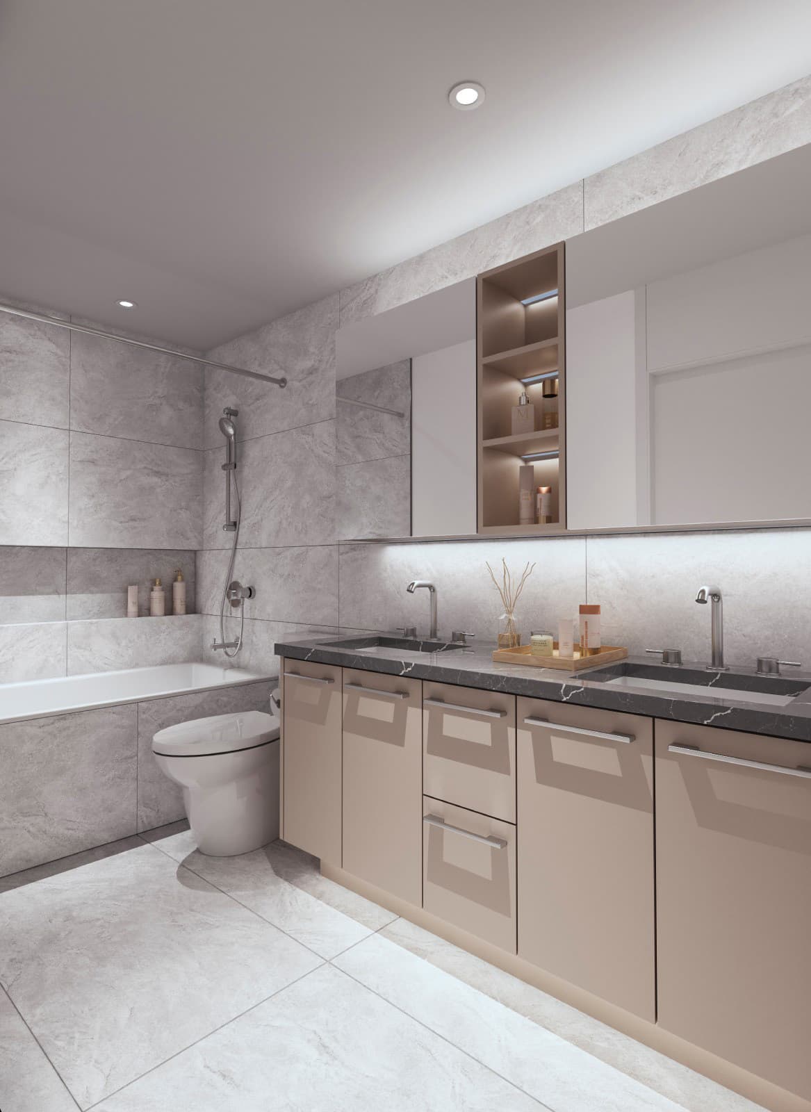 Oasis at Concord Brentwood – A modern bathroom featuring a light-tan double vanity with a dark marble countertop, polished chrome fixtures, and a large mirrored medicine cabinet with under-cabinet LED lighting. The floor and walls are lined with large grey stone-look tiles, leading back to a modern toilet and a deep tub with a hand-held shower fixture.