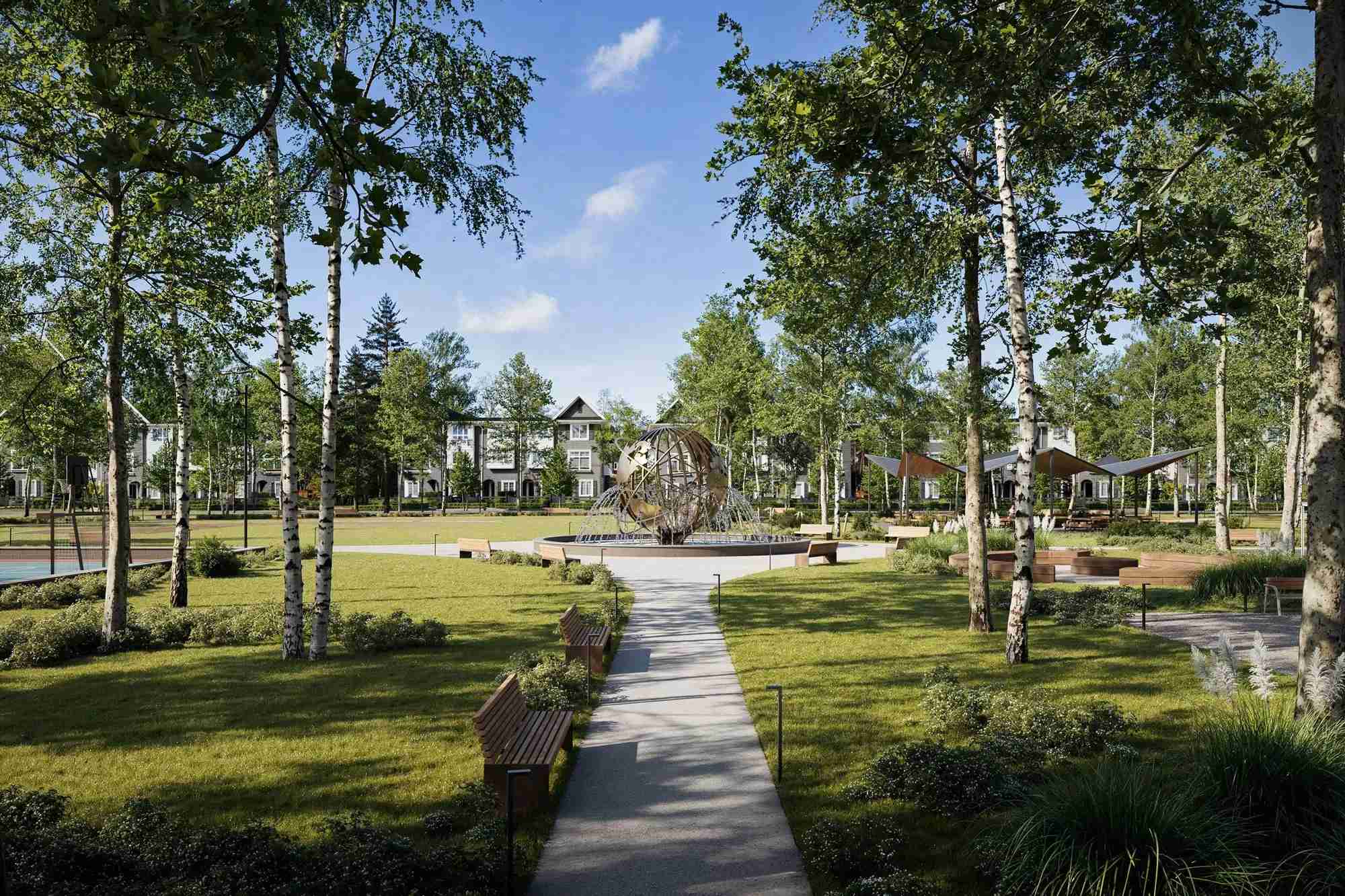 Queens Townhomes – A sunny central community park framed by birch trees and manicured lawns features a large spherical globe water fountain at the center. Paved walking paths, wooden park benches, shade canopies, and a sports court are spread throughout the grounds with modern townhomes in the background.