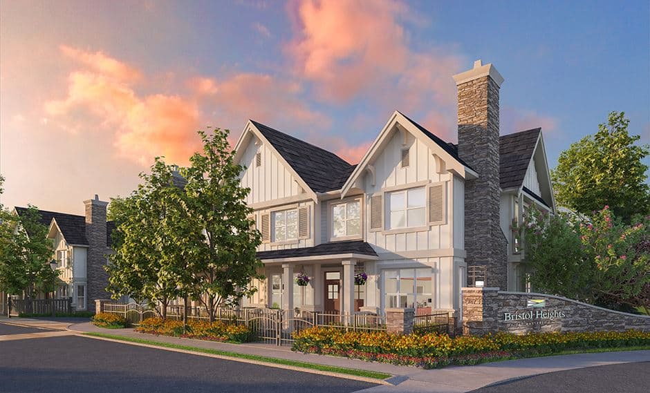 Bristol Heights at Westerleigh – Two-storey craftsman-style townhome exterior at sunset with a stone chimney, front porch, and the Bristol Heights entrance sign in the foreground.